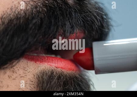 Berlin, Deutschland. Juli 2024. Ein Mann benutzt roten Lippenstift. Der 29. Juli ist der Tag des Lippenstifts. Quelle: Hannes P. Albert/dpa/Alamy Live News Stockfoto