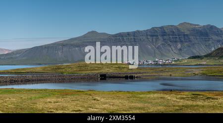 Malerisches Küstendorf in der Nähe von Bergen und ruhigen Gewässern unter klarem blauem Himmel Stockfoto