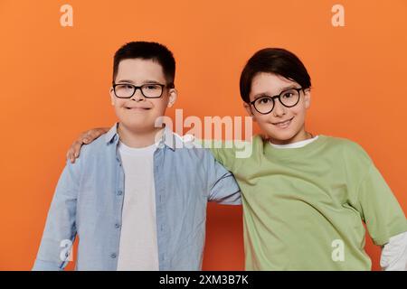 Zwei kleine Jungen, einer mit Down-Syndrom, posieren für ein Foto mit den Armen umeinander. Stockfoto