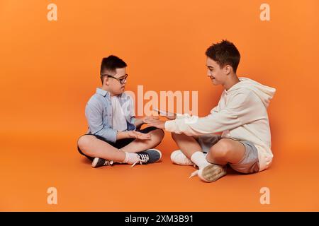 Zwei Jungs, einer mit Down-Syndrom, sitzen auf dem Boden und spielen ein Spiel. Stockfoto