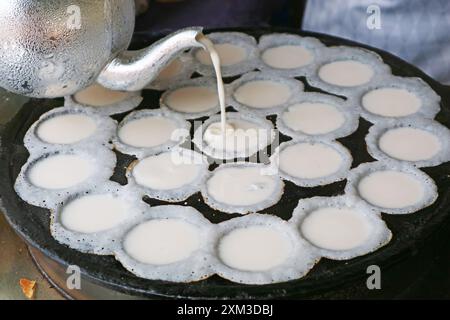 Kanom krok oder Thai Coconut Milk Pancakes Teig wird in die Pan's Holes gegossen Stockfoto