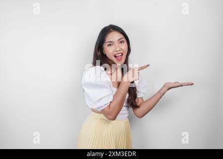 Eine fröhliche asiatische Frau zeigt neben ihr einen Kopierraum, isoliert von weißem Hintergrund. Stockfoto