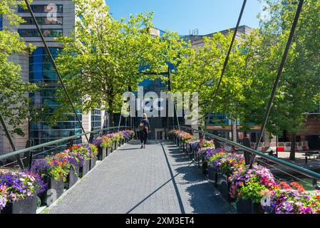 Fußgängerbrücke mit bunten Blumen über den Kanal zwischen dem Brindley Place und dem International Convention Centre ICC im Stadtzentrum von Birmingham Stockfoto