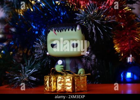 Funko Pop Actionfigur der beliebten Horror-fiktionalen Figur Frankensteins Monster. Weihnachtsbaum, helle Ornamente, goldene Geschenkboxen, Feiertage. Stockfoto