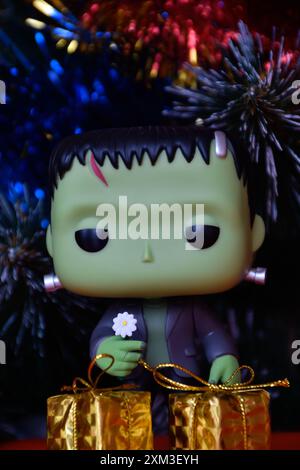 Funko Pop Actionfigur der beliebten Horror-fiktionalen Figur Frankensteins Monster. Weihnachtsbaum, helle Ornamente, goldene Geschenkboxen, Feiertage. Stockfoto