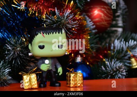 Funko Pop Actionfigur der beliebten Horror-fiktionalen Figur Frankensteins Monster. Weihnachtsbaum, helle Ornamente, goldene Geschenkboxen, Feiertage. Stockfoto