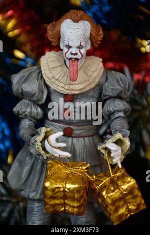 NECA Actionfigur von Pennywise Clown aus dem Horrorfilm IT. Spielzeug mit herunterhängender Zunge, Nahansicht. Kleine, helle Geschenkboxen, Weihnachtsbaum. Stockfoto