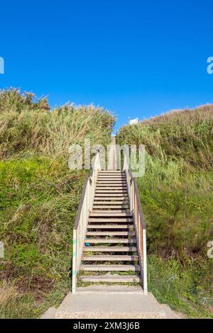 Holztreppen führen an einem sonnigen Tag von der Klippe auf den Sand, Holztreppen Stockfoto