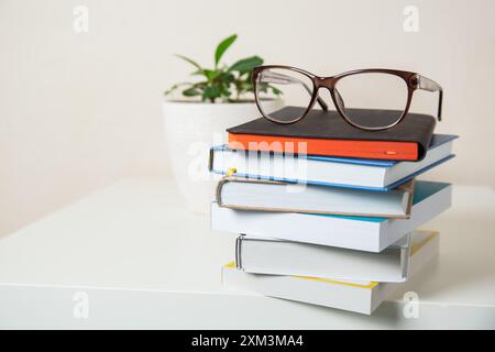 Ein Stapel Bücher mit einer Brille auf dem Arbeitstisch, Kopierraum Stockfoto