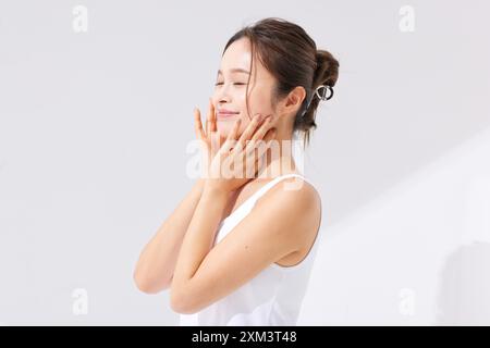 Asiatische Frau, Die Ihr Gesicht Mit Den Händen Berührt Stockfoto