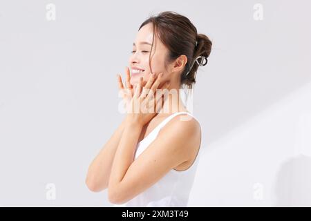 Asiatische Frau, Die Ihr Gesicht Mit Den Händen Berührt Stockfoto