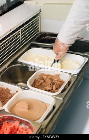 Der Verkäufer legt eine Kugel Eiscreme-Schaufel Stockfoto