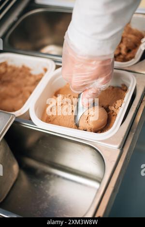Der Verkäufer legt eine Kugel Eiscreme-Schaufel Stockfoto