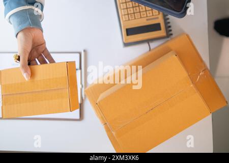 Paketboxen werden verpackt und können an Kunden gesendet werden, die Online-Bestellungen im System des Online-Shops aufgegeben haben. Ein kleiner KMU-Geschäftsmann Stockfoto