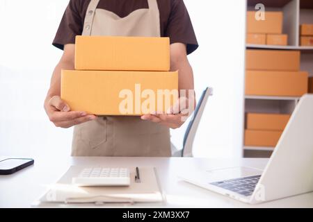 Paketboxen werden verpackt und können an Kunden gesendet werden, die Online-Bestellungen im System des Online-Shops aufgegeben haben. Ein kleiner KMU-Geschäftsmann Stockfoto