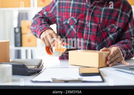 Paketboxen werden verpackt und können an Kunden gesendet werden, die Online-Bestellungen im System des Online-Shops aufgegeben haben. Ein kleiner KMU-Geschäftsmann Stockfoto