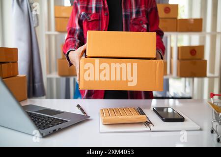 Paketboxen werden verpackt und können an Kunden gesendet werden, die Online-Bestellungen im System des Online-Shops aufgegeben haben. Ein kleiner KMU-Geschäftsmann Stockfoto