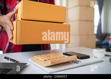 Paketboxen werden verpackt und können an Kunden gesendet werden, die Online-Bestellungen im System des Online-Shops aufgegeben haben. Ein kleiner KMU-Geschäftsmann Stockfoto