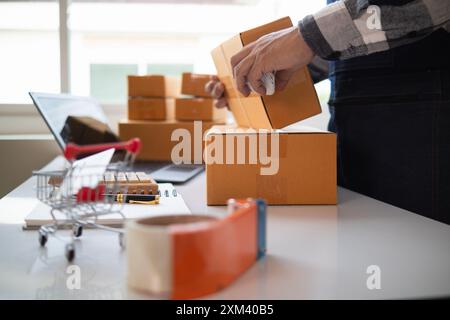 Paketboxen werden verpackt und können an Kunden gesendet werden, die Online-Bestellungen im System des Online-Shops aufgegeben haben. Ein kleiner KMU-Geschäftsmann Stockfoto