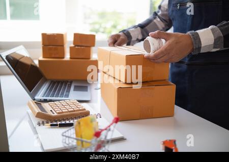 Paketboxen werden verpackt und können an Kunden gesendet werden, die Online-Bestellungen im System des Online-Shops aufgegeben haben. Ein kleiner KMU-Geschäftsmann Stockfoto