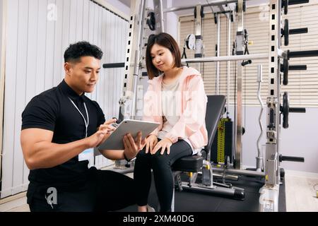Asiatische Männer und Frauen in Einem Fitnessstudio mit Einem Tablet Stockfoto