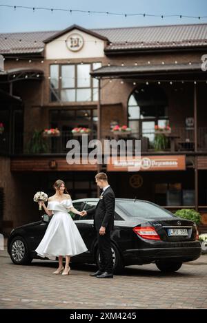 Junges Paar Braut und Bräutigam in einem weißen, kurzen Kleid, das im Regen läuft Stockfoto