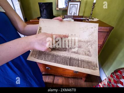 Ein Freiwilliger zeigt ein Foto von Menschen, die während einer totalen Sonnenfinsternis am 7. August 1869 auf dem Wylie House in Bloomington, Indiana, standen. Stockfoto