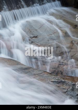 Abstraktes Detail des Wassers, das über Felsen in einem Gebirgsbach in der Nähe von Ballachulish, Glencoe, Schottland, Großbritannien fließt Stockfoto