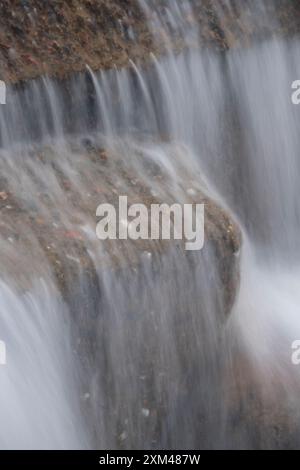 Abstraktes Detail des Wassers, das über Felsen in einem Gebirgsbach in der Nähe von Ballachulish, Glencoe, Schottland, Großbritannien fließt Stockfoto