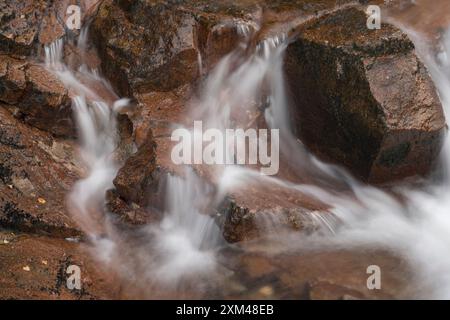 Abstraktes Detail des Wassers, das über Felsen in einem Gebirgsbach in der Nähe von Ballachulish, Glencoe, Schottland, Großbritannien fließt Stockfoto