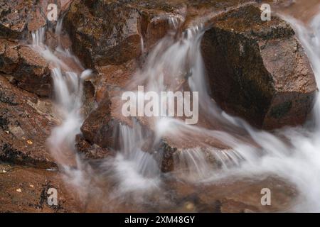 Abstraktes Detail des Wassers, das über Felsen in einem Gebirgsbach in der Nähe von Ballachulish, Glencoe, Schottland, Großbritannien fließt Stockfoto