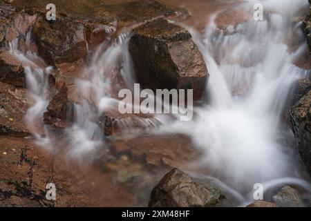 Abstraktes Detail des Wassers, das über Felsen in einem Gebirgsbach in der Nähe von Ballachulish, Glencoe, Schottland, Großbritannien fließt Stockfoto