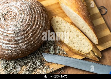 Brot und Baguette auf einem Holzbrett mit Weizenohren geschnitten. Ausgewählter Fokus. Hochwertige Fotos Stockfoto