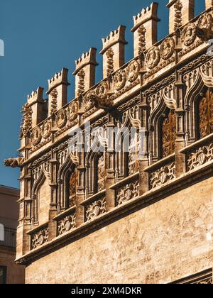 Detaillierte Ansicht der gotischen Architektur der Llotja de la Seda in Valencia, Spanien, mit komplizierten Schnitzereien und kunstvollen Elementen vor einem klaren blauen Himmel. Stockfoto