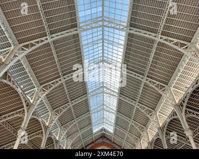 Innenansicht einer historischen Markthalle mit Glasdach, die architektonische Details und das Zusammenspiel von Licht und Schatten in Valencia, Spanien, zeigt. Stockfoto