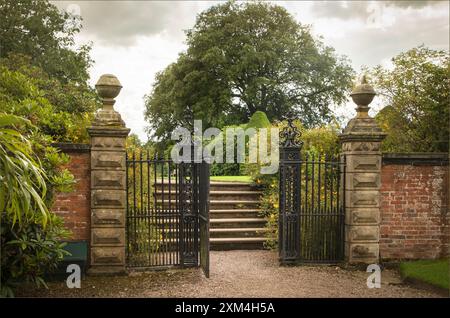 Arley, West Cheshire, Großbritannien - 17. Juli 2024 - Tor zu alten Sandsteintorpfosten, die zu Stufen in einem Garten führen Stockfoto