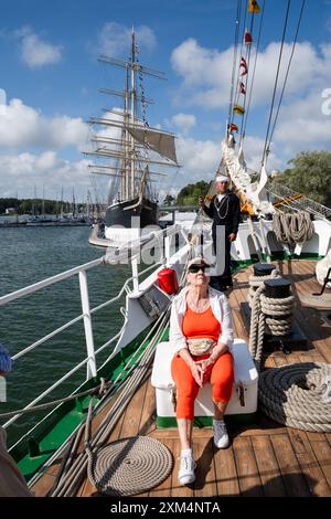 MARIEHAMN, Åland, FINNLAND - 25. JULI 2024: Ein Besucher sitzt auf dem Bug des Hochschiffs Guayas aus Ecuador und bewundert die Aussicht mit dem Museumsschiff Pommern im Hintergrund. Tag zwei der dreitägigen Åland-Etappe des Tall Ships Race 2024 im Haupthafen Mariehamn, Åland, Finnland. Foto: Rob Watkins/Alamy Live News. INFO: Das Tall Ships Race ist eine jährliche Segelveranstaltung mit historischen und modernen Großschiffen. Es fördert internationale Freundschaft und Jugendausbildung und zieht Teilnehmer und Zuschauer weltweit an, um maritimes Erbe und die Kunst des traditionellen Segelns zu feiern. Stockfoto