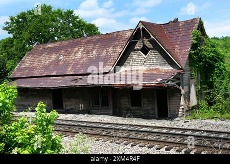 Old Limestone Train Depot befindet sich neben alten Gleisen in Kalkstein, Tennessee. Blechdach und Lebkuchenholzarbeiten sind verfallen. Stockfoto