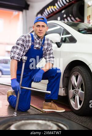 Der qualifizierte Mechaniker wechselt die Reifen des Fahrzeugs im Autodienst Stockfoto