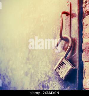 Ein altes Vorhängeschloss hängt am Griff der Metalltür. Öffnen der Tür. Stockfoto