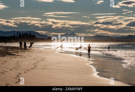 Surfer schlendern in der Sonne am Strand in Byron Bay, New South Wales, Australien. Stockfoto