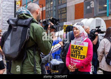 Manchester, Großbritannien. JULI 2024. Aktivist wird interviewt, als Demonstranten sich zu Demonstrationen gegen ein Video versammelten, das vom Flughafen Manchester veröffentlicht wurde, in dem GMP-Feuerwaffenoffiziere gesehen wurden, die Gewalt gegen Demonstranten einsetzten, wobei der Vorfall an das IPCC verwiesen wurde. Die Demonstranten blockierten die Straßenbahnen und den Verkehr am Petersplatz ohne Polizeieingriff. Die Demonstranten zerstreuten sich nach etwa 2 Stunden. Credit Milo Chandler/Alamy Live News Stockfoto