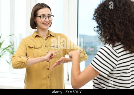 Junge Frauen, die Gebärdensprache für die Kommunikation in Innenräumen verwenden Stockfoto