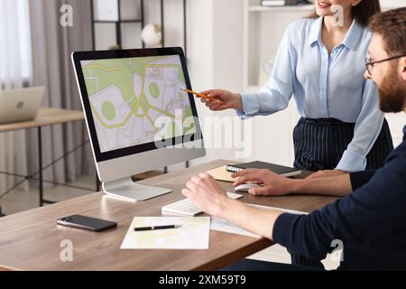 Kartografen arbeiten mit Katasterkarten am Computer am Tisch im Büro Stockfoto