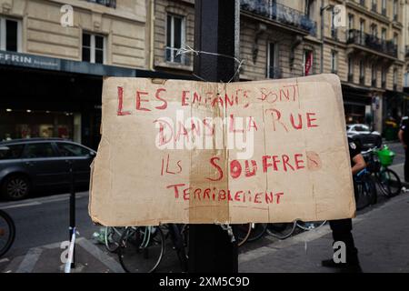Ein Plakat, auf dem steht: "Die Kinder sind auf der Straße. Sie leiden furchtbar, vor dem Rathaus des 18. Arrondissements gesehen. Dutzende obdachloser Migrantenfamilien verbrachten drei Tage und zwei Nächte an Ort Jules Joffrin vor dem Rathaus des 18. Arrondissements in Paris, um ihr Recht auf Wohnung zu fordern. Eine Polizeieinheit bildete einen Umkreis, der es niemandem erlaubte, das Haus zu verlassen oder zu betreten, was dazu führte, dass die Familien getrennt wurden. Erst am dritten Tag fand die Präfektur Unterkunft in der Ile de France, aber sie wusste nicht, wie lange die Unterkunft dauern würde. (Foto b Stockfoto