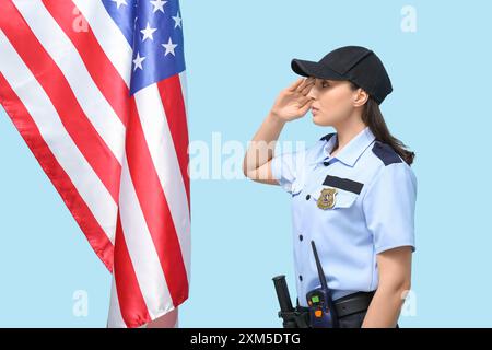 Grüßende Polizistin und Flagge der USA auf blauem Hintergrund Stockfoto