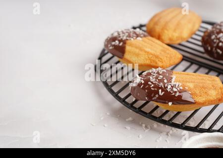 Gitter mit köstlichen Madeleinen mit Schokoladencreme und Kokosflocken auf weißem Hintergrund Stockfoto