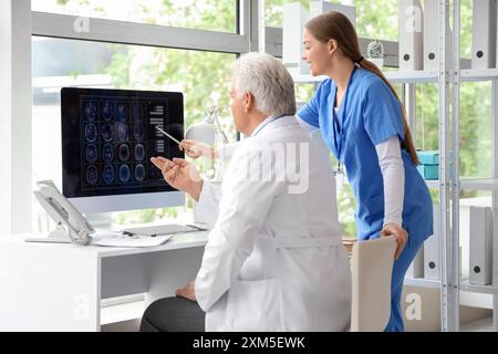 Reifer Arzt mit Krankenschwester, der MRT-Scan am Computerbildschirm in der Klinik studiert Stockfoto