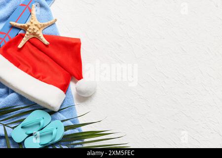 Weihnachtsmann Hut, Flipflops, Seesterne und Palmenzweig auf Handtuch auf weißem Hintergrund. Draufsicht Stockfoto