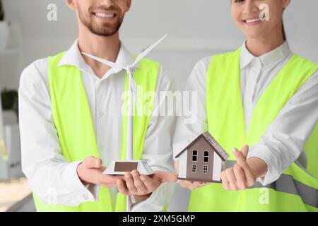 Junge Ingenieure mit Windenergieanlage und Hausmodell machen Herzgeste im Büro, Nahaufnahme Stockfoto